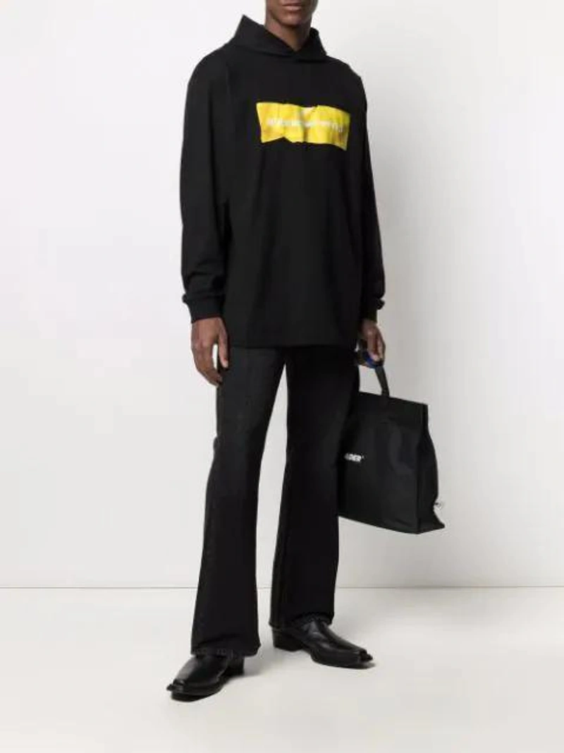Farfetch's Post | Wearing: Alexander Wang Two-tone Logo-print Hoodie In Black; Acne Studios 1992 Jeans In Black; Ader Error Logo Holdall In Black