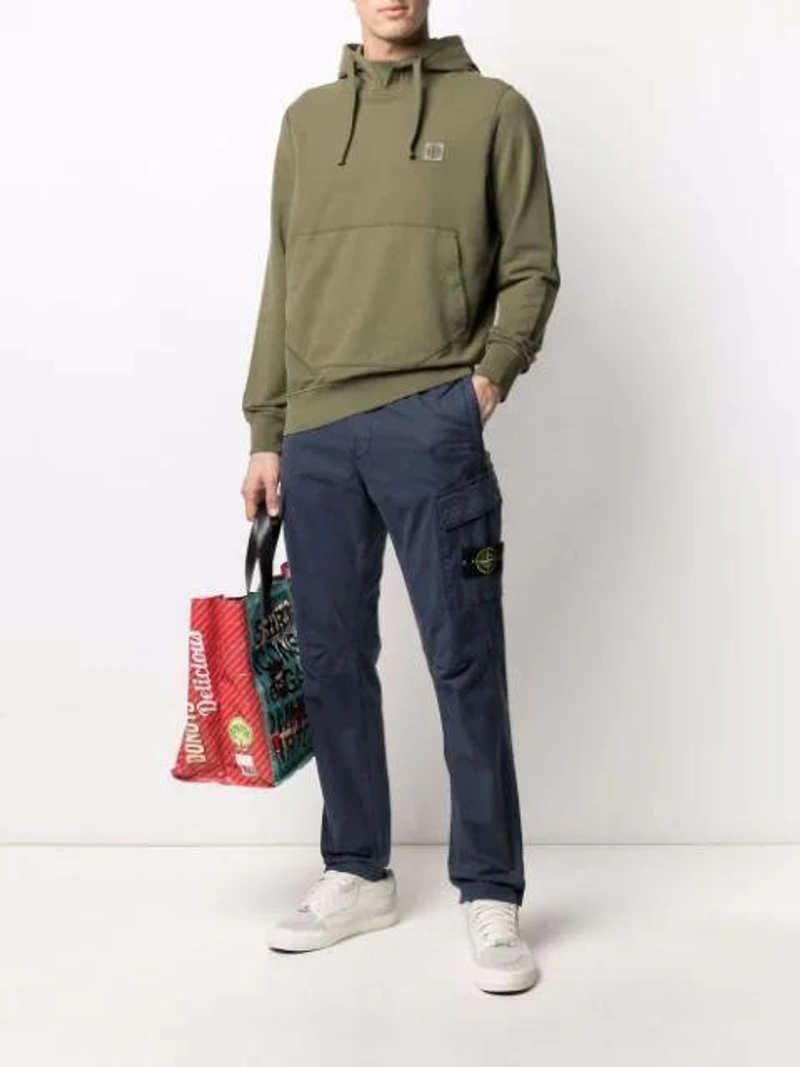 Farfetch's Post | Wearing: Stone Island Logo-patch Drawstring Hoodie In Green; Stone Island Logo-patch Cargo Trousers In Blue; Comme Des Garçons Shirt Delicious Logo Tote In Purple