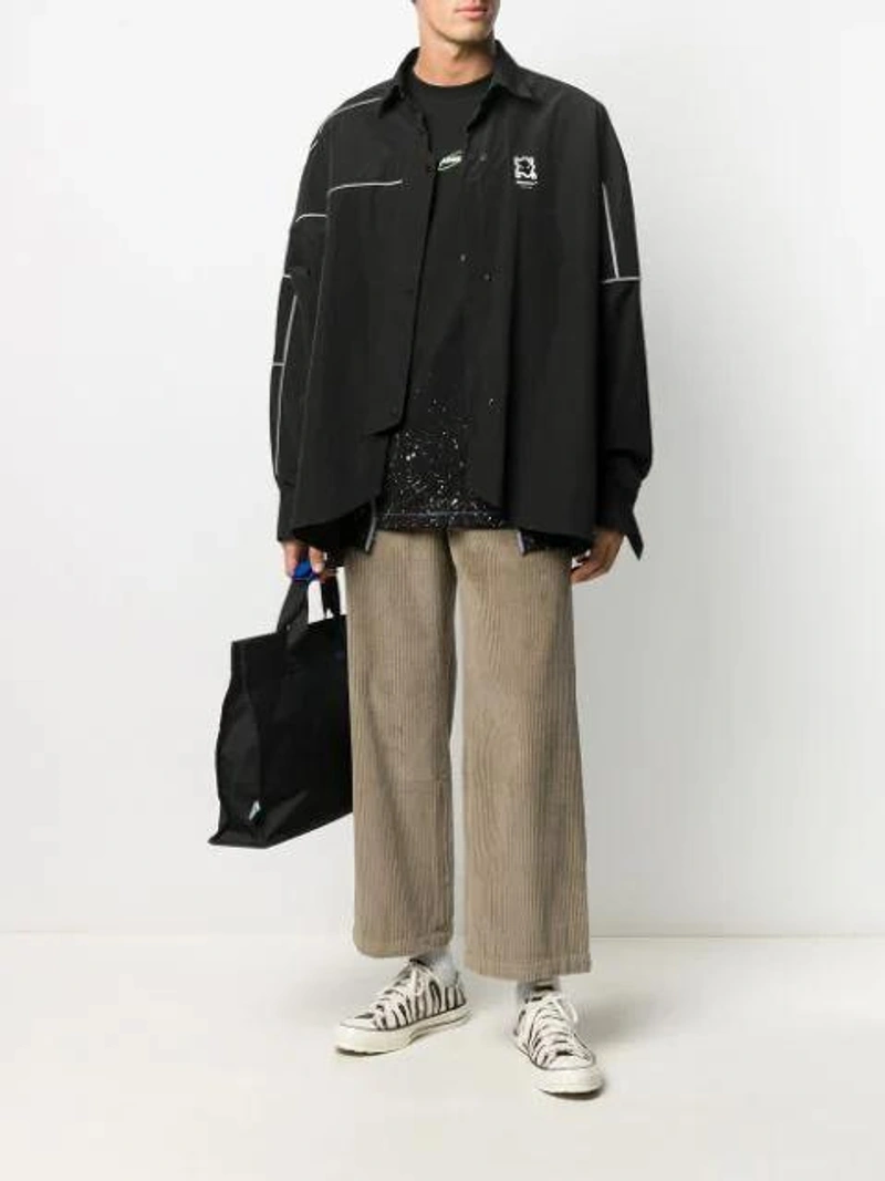 Farfetch's Post | Wearing: Ader Error Oversized Reflector Jacket In Black; Ader Error Cosmo Paint-splatter T-shirt In Black; Ader Error Logo-embroidered Wide-leg Corduroy Trousers In Brown