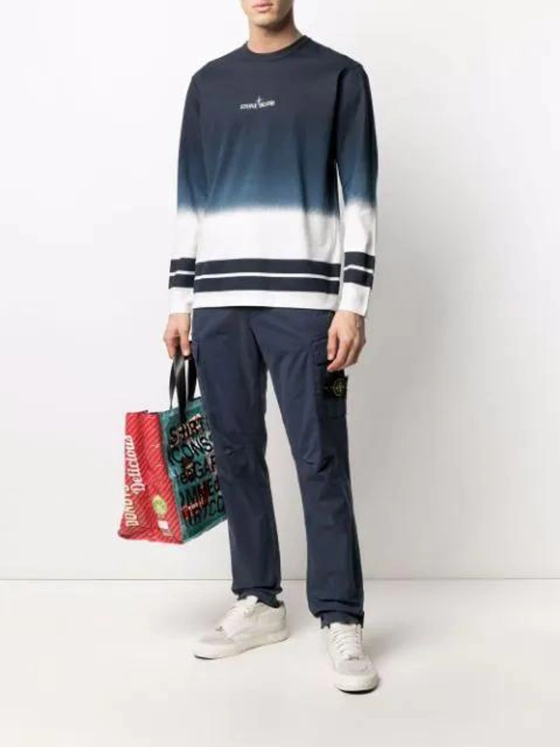 Farfetch's Post | Wearing: Stone Island Long Sleeve Logo Graphic Tee In Dark Blue; Stone Island Logo-patch Cargo Trousers In Blue; Comme Des Garçons Shirt Delicious Logo Tote In Purple