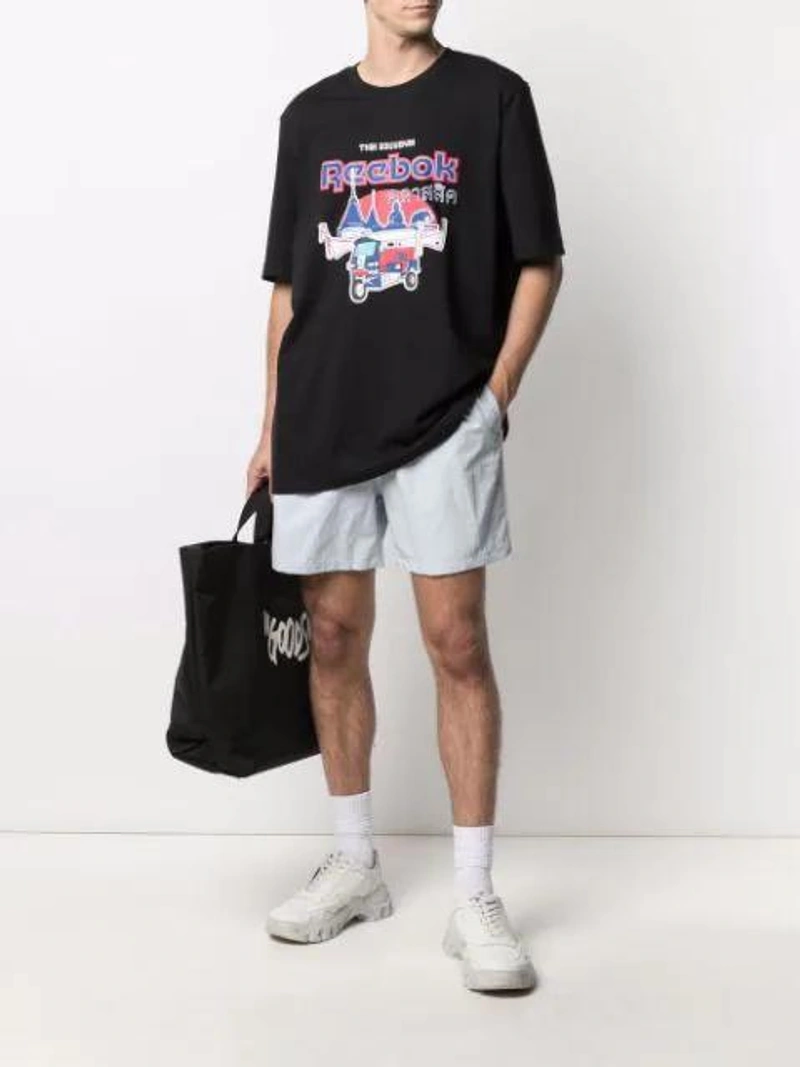 Farfetch's Post | Wearing: Reebok Graphic-print T-shirt In Black; Asceno Rivello Wide Leg Linen Trousers In White; Birkenstock Arizona Sandals In Black