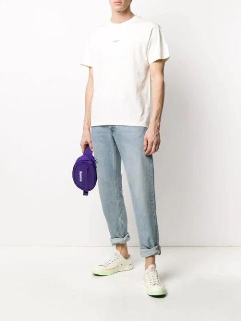 Farfetch's Post | Wearing: Sunflower Washed Straight Leg Jeans In Blue; Represent Logo-print Cotton T-shirt In Neutrals; Neighborhood X Porter Technical Nylon Pouch In White
