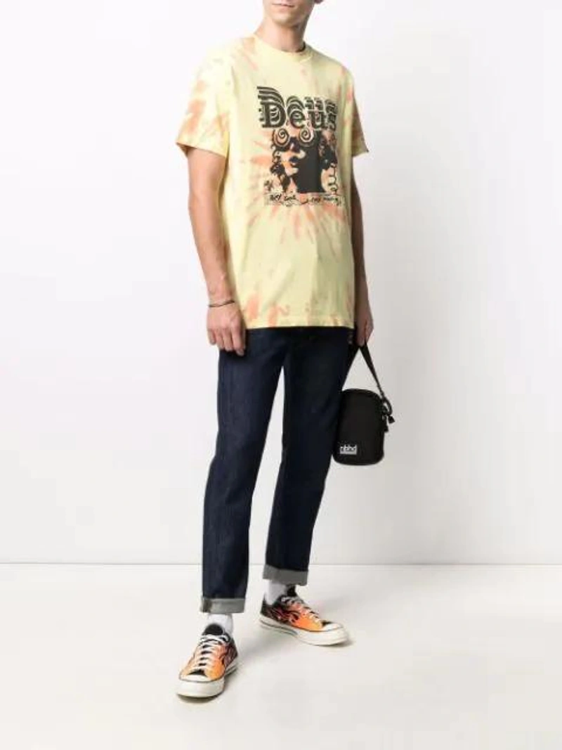 Farfetch's Post | Wearing: Converse Multicoloured Chuck 70 Flame Low Top Sneakers In Black; Deus Ex Machina Graphic-print Tie-dye T-shirt In Yellow; Orslow Blue Superslim Skinny Jeans