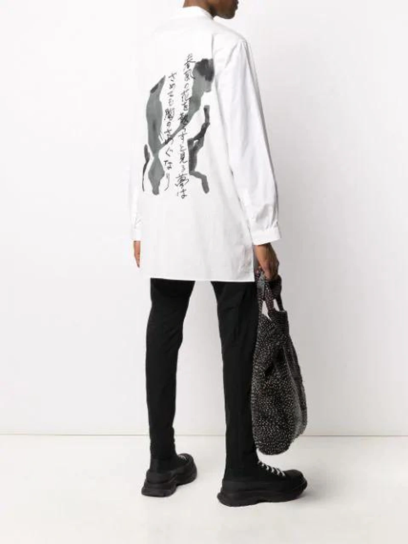 Farfetch's Post | Wearing: Alexander Mcqueen Chunky High-top Sneakers In Black; Yohji Yamamoto Rear-print Oversized Shirt In White; Masnada Tapered Drop-crotch Trousers In Black