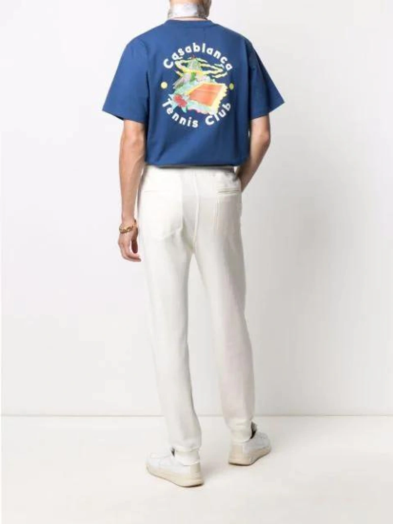 Farfetch's Post | Wearing: Casablanca Casa Tennis Club Island Double T-shirt Navy In Blue; Brunello Cucinelli Jersey Sweatpants In White; Versace Gold Tone Medusa Chain Bracelet In K41t Nero Oro
